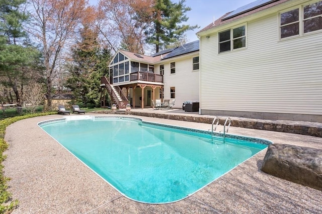 outdoor pool with stairs, a patio area, a sunroom, and a deck