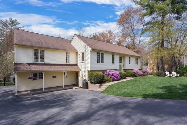 view of front facade with a shingled roof, a front lawn, and aphalt driveway
