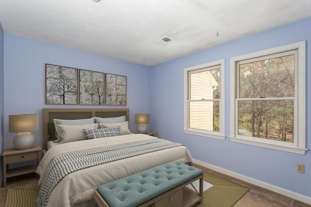 bedroom with baseboards, carpet, visible vents, and multiple windows