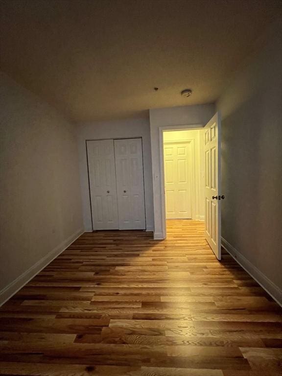 unfurnished bedroom with wood finished floors, a closet, and baseboards