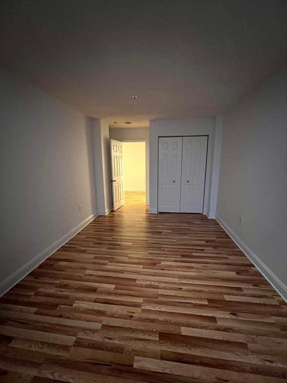 unfurnished bedroom featuring a closet, baseboards, and wood finished floors