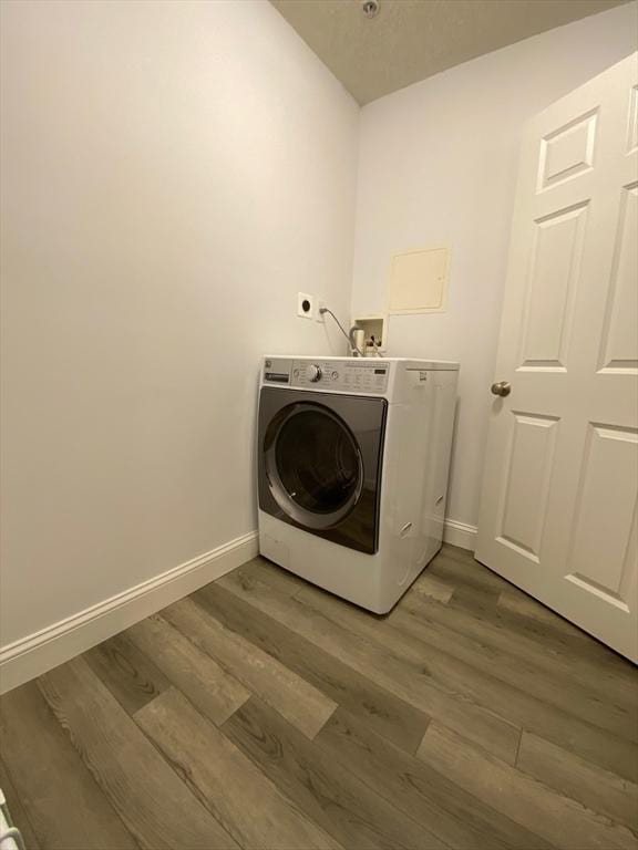 washroom featuring laundry area, washer / clothes dryer, wood finished floors, and baseboards