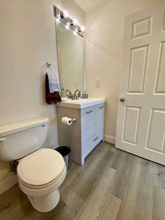 bathroom featuring toilet, vanity, baseboards, and wood finished floors