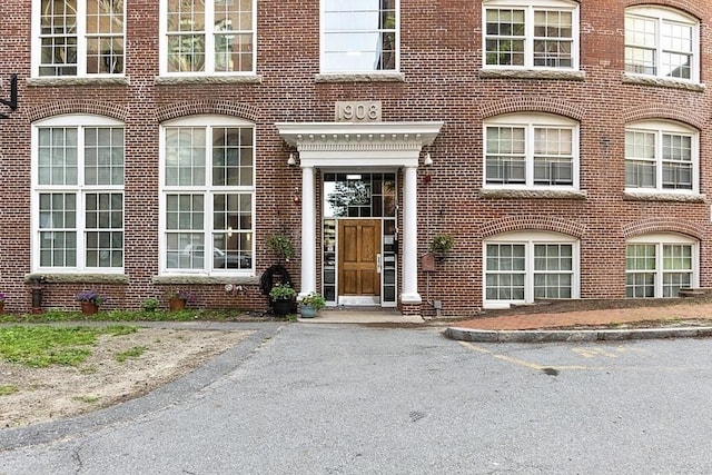 property entrance with uncovered parking and brick siding