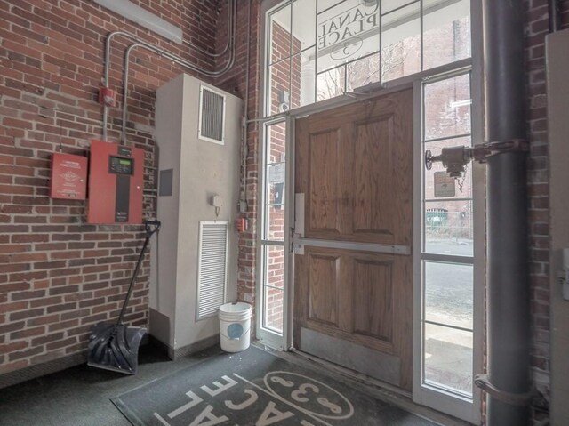 foyer with a wealth of natural light, visible vents, and brick wall