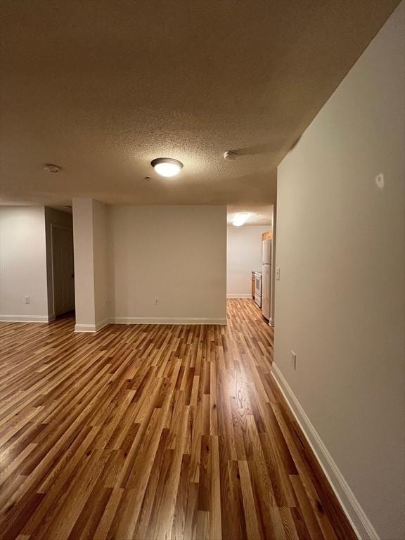 empty room with baseboards, a textured ceiling, and wood finished floors