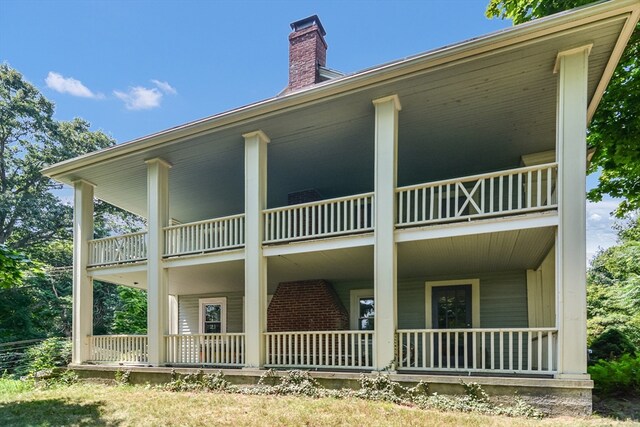 back of property featuring a balcony and covered porch