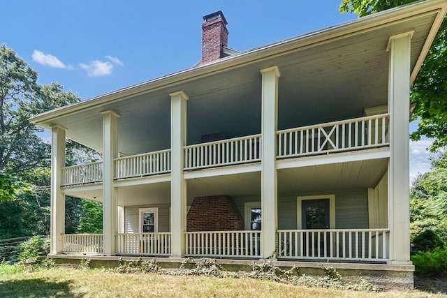 back of house featuring a porch and a balcony