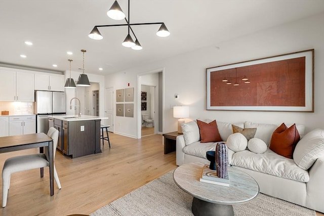 living area with recessed lighting, light wood finished floors, and a chandelier