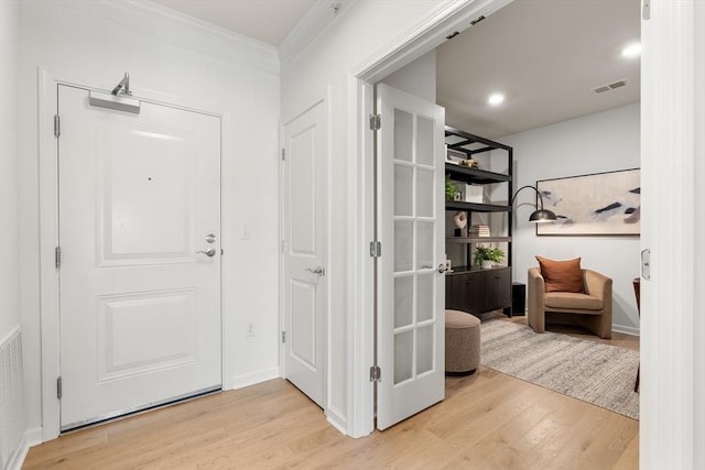 foyer with crown molding, wood finished floors, and visible vents