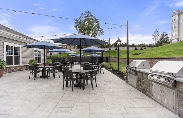 view of patio with area for grilling, an outdoor kitchen, fence, and outdoor dining space