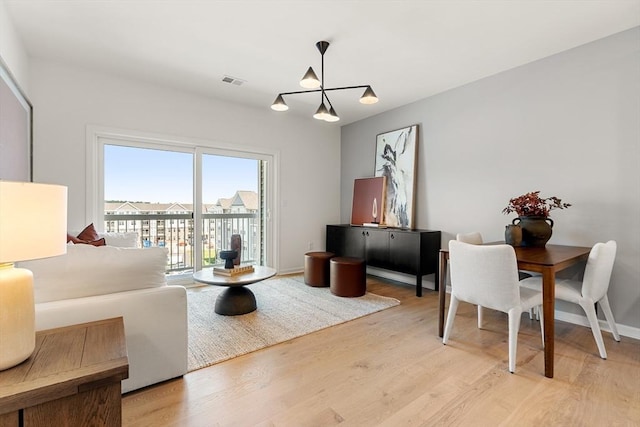 living area featuring light wood-style floors, a chandelier, and visible vents