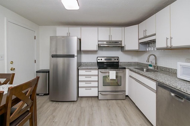 kitchen with a sink, stainless steel appliances, under cabinet range hood, and light wood-style flooring