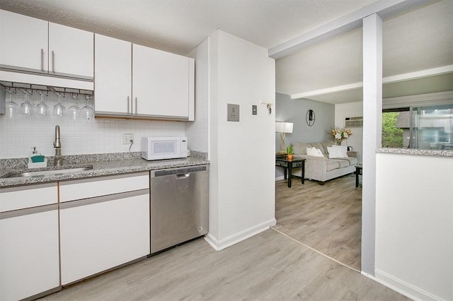kitchen with stainless steel dishwasher, light wood finished floors, a sink, white cabinetry, and white microwave