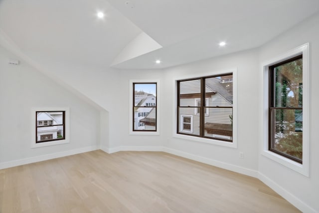 additional living space featuring lofted ceiling, plenty of natural light, and light hardwood / wood-style floors