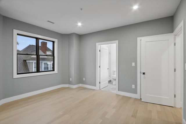 unfurnished bedroom with light hardwood / wood-style flooring and ensuite bath