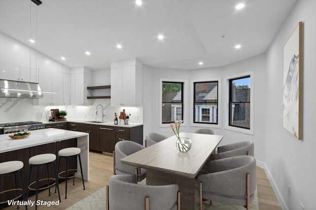 dining room with lofted ceiling, sink, and light hardwood / wood-style floors