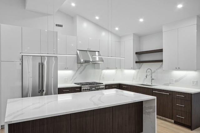 kitchen featuring a kitchen island, dark brown cabinetry, stainless steel appliances, sink, and light hardwood / wood-style floors