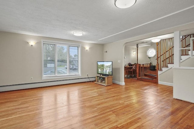 0 Steeple View Way, Leominster, MA 01453 - unfurnished living room with arched walkways, wood finished floors, stairs, a baseboard radiator, and a textured ceiling