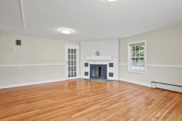 0 Steeple View Way, Leominster, MA 01453 - unfurnished living room featuring wood finished floors, a large fireplace, a baseboard radiator, and a textured ceiling
