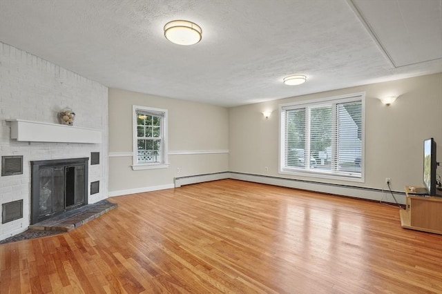 0 Steeple View Way, Leominster, MA 01453 - unfurnished living room featuring wood finished floors, healthy amount of natural light, a fireplace, a baseboard heating unit, and a textured ceiling