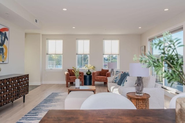 living room featuring light wood-type flooring, plenty of natural light, visible vents, and recessed lighting