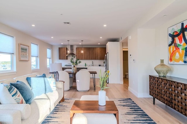 living room featuring light wood finished floors, baseboards, visible vents, and recessed lighting