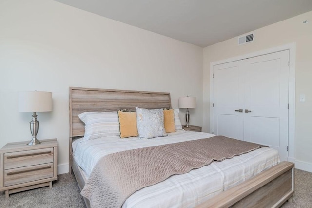 carpeted bedroom with a closet, visible vents, and baseboards