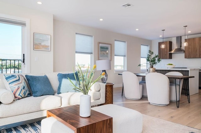 living room featuring light wood-type flooring, visible vents, and recessed lighting