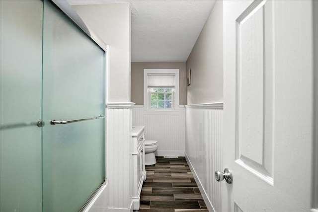 40 Richard Ave, Shrewsbury, MA 01545 - bathroom featuring toilet, wood finished floors, a wainscoted wall, and combined bath / shower with glass door