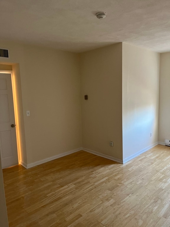 unfurnished room featuring a baseboard radiator and light wood-type flooring