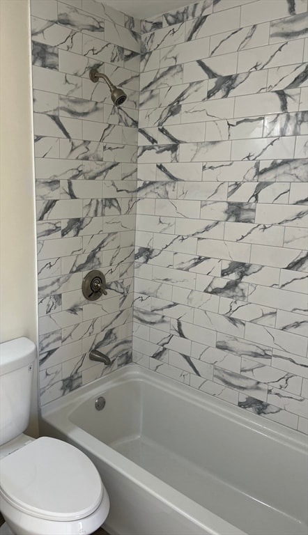 bathroom featuring tiled shower / bath combo and toilet