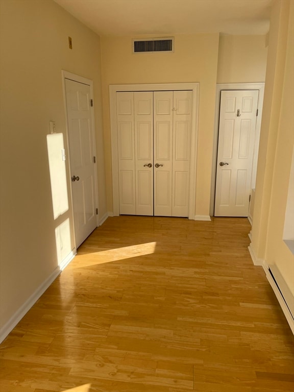 hallway with baseboard heating and light hardwood / wood-style floors