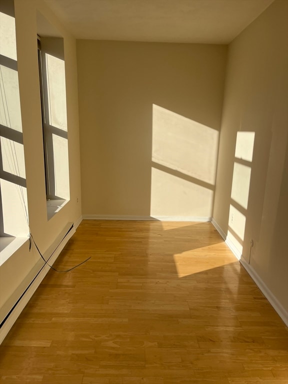 unfurnished room with baseboard heating and light hardwood / wood-style flooring