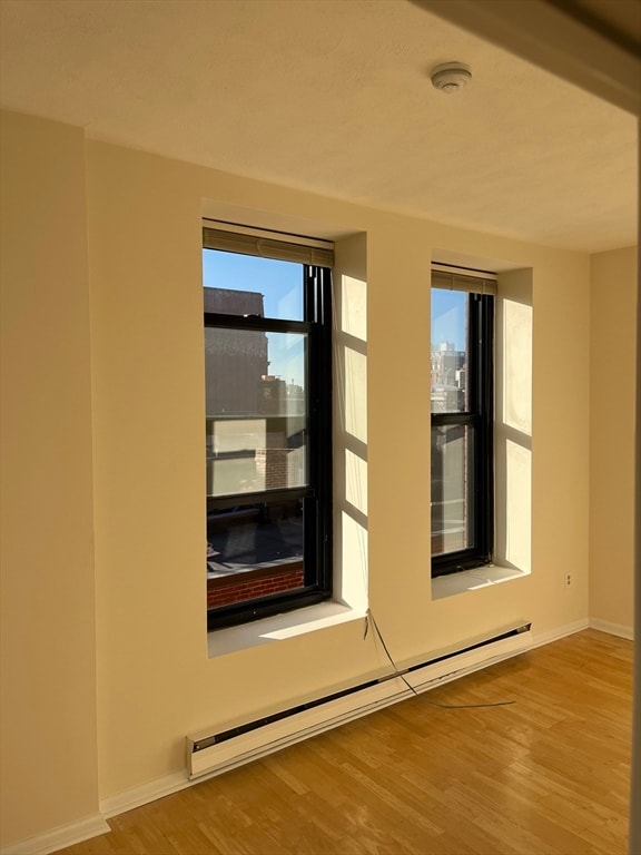 doorway featuring wood-type flooring and a baseboard heating unit