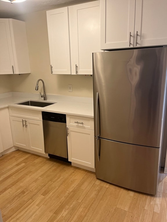 kitchen featuring white cabinetry, sink, appliances with stainless steel finishes, and light hardwood / wood-style flooring