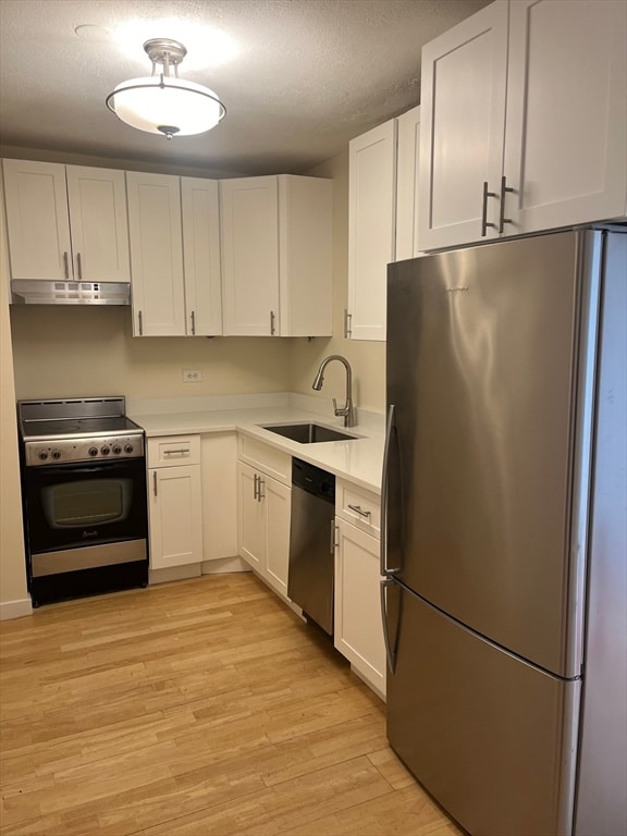 kitchen with white cabinetry, sink, light hardwood / wood-style flooring, a textured ceiling, and appliances with stainless steel finishes