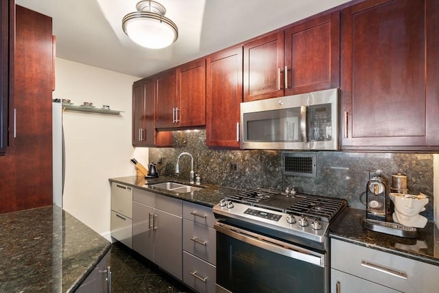 8 Whittier Pl Unit 17E, Boston, MA 02114 - kitchen featuring appliances with stainless steel finishes, a sink, granite tiled floors, dark brown cabinets, and dark stone countertops