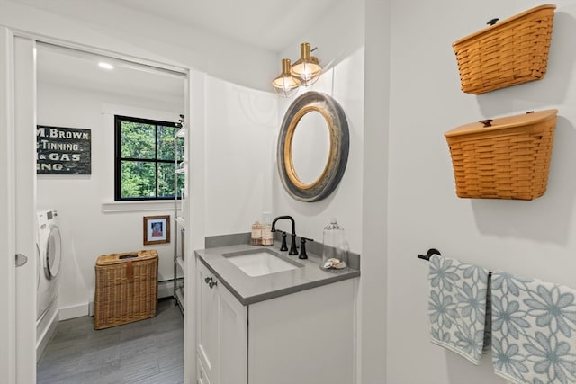 bathroom with vanity, hardwood / wood-style flooring, independent washer and dryer, and a baseboard radiator