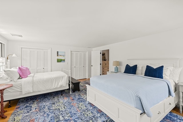 bedroom with two closets and hardwood / wood-style flooring