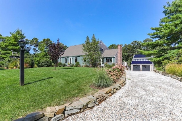 view of front of house featuring an outbuilding, gravel driveway, a chimney, a front lawn, and a garage