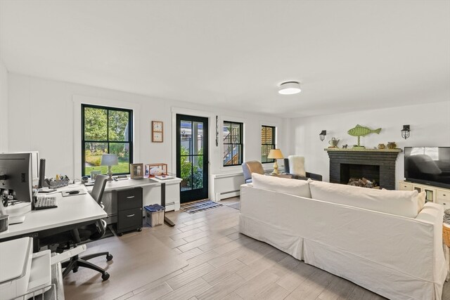 interior space featuring a baseboard radiator, a brick fireplace, and light hardwood / wood-style floors