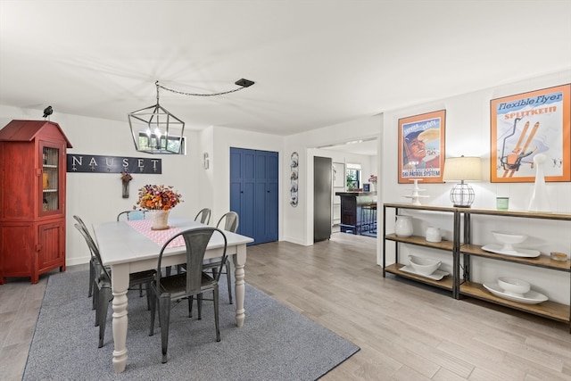 dining space with light wood-type flooring and a notable chandelier