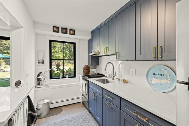 kitchen with a baseboard radiator, backsplash, light stone counters, and light wood-type flooring