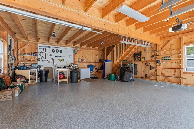 garage with a workshop area, a garage door opener, and wooden walls