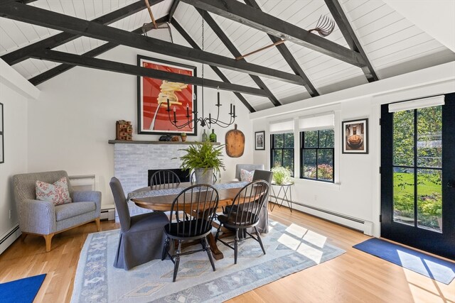 dining area featuring a baseboard radiator, light hardwood / wood-style floors, lofted ceiling with beams, and a fireplace