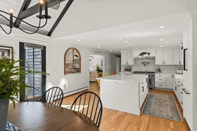 kitchen featuring lofted ceiling with beams, white cabinetry, a kitchen island, and light hardwood / wood-style floors