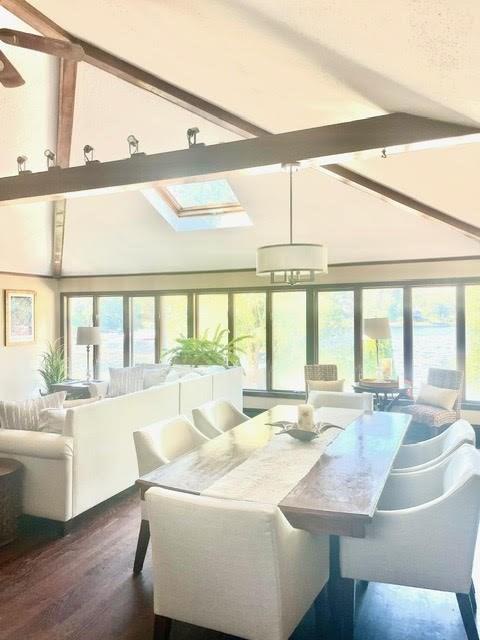 sunroom / solarium featuring vaulted ceiling with skylight and plenty of natural light