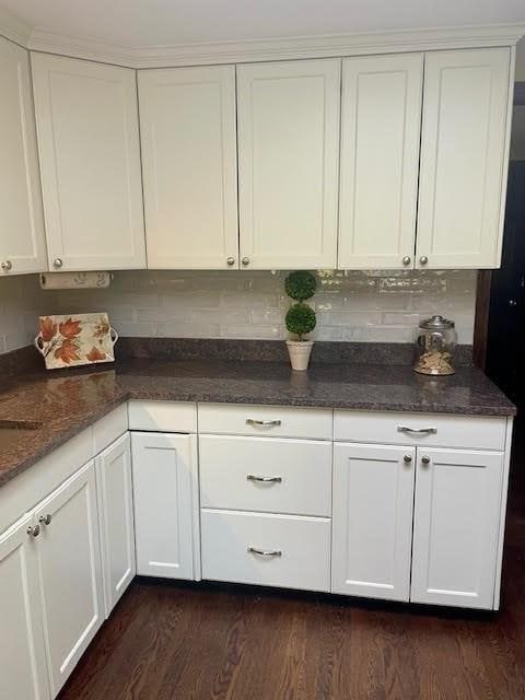 kitchen featuring tasteful backsplash, white cabinetry, dark wood finished floors, and dark stone counters