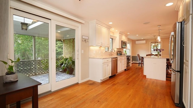 36 Jean Dr, North Attleboro, MA 02760 - kitchen with appliances with stainless steel finishes, white cabinetry, backsplash, light wood finished floors, and a wall mounted air conditioner